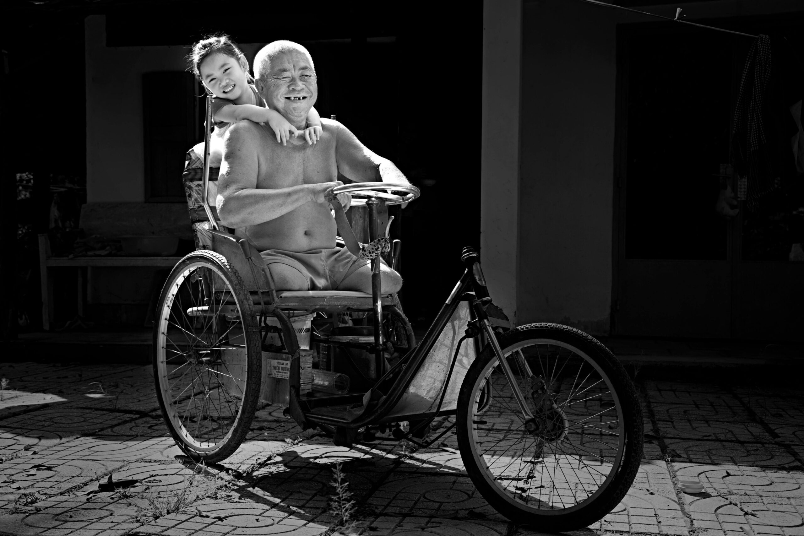 A joyful moment of a father and child on a tricycle, captured in black and white.